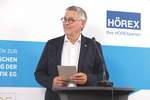 Vorstand Mario Werndl vor Wand mit HÖREX Logo